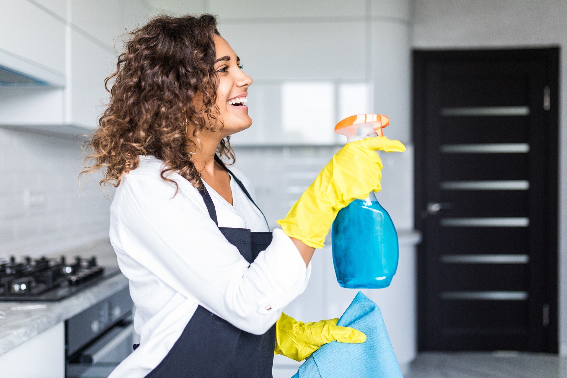 Huishoudelijke hulp maakt lachend de keuken schoon